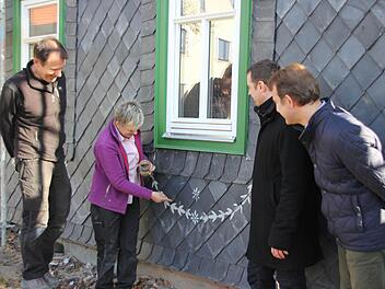 Franz Schirmer und Petra Zenkel-Schirmer (von links) zeigen, wie die Verzierungen auf der Schieferfassade angebracht werden. Mit im Bild sind (von rechts): Kreisheimatpfleger Rudolf Wachter und Hausbesitzer Daniel Rudolph.  Foto: Friedwald Schedel
