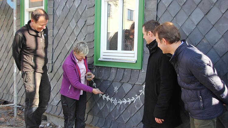 Franz Schirmer und Petra Zenkel-Schirmer (von links) zeigen, wie die Verzierungen auf der Schieferfassade angebracht werden. Mit im Bild sind (von rechts): Kreisheimatpfleger Rudolf Wachter und Hausbesitzer Daniel Rudolph.  Foto: Friedwald Schedel