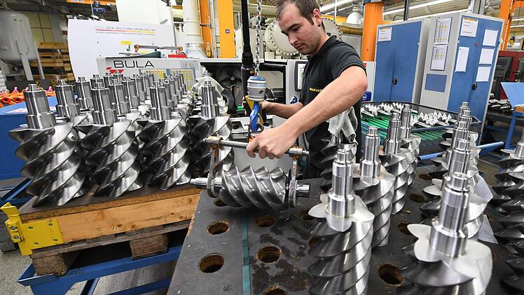 Hendrik Schmidt von der Firma Kaeser Kompressoren in Coburg greift eine Rotorwelle, um sie für den maschinellen Feinschliff vorzubereiten. Sie ist später wichtiger Bestandteil eines Kompressors. Foto: Ronald Rinklef