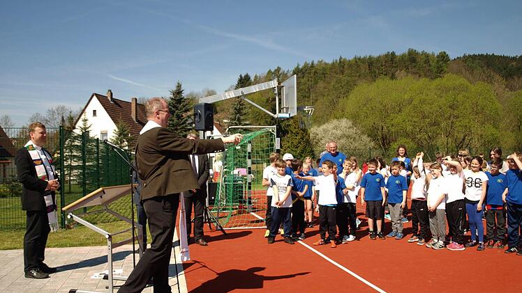 Regionaldekan Thomas Teuchgräber segnet die Außensportanlagen mit Weihwasser. Ganz links Pfarrer Andreas Krauter. Foto: Susanne Deuerling
