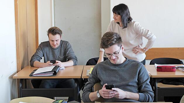 Tom Mei&szlig;ner (18), Niklas L&ouml;chle (20) und Lehrerin Lydia Friedrich (38) stellen die Nutzung von Smartphones im Unterricht nach.  Foto: Valerie Tordai