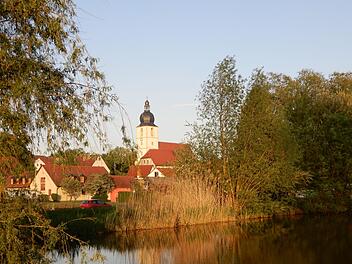 Blick über den Dorfsee: Die Rentweinsdorfer Dreieinigkeitskirche, das größte evangelische Gotteshaus der Umgegend, bildet den Mittelpunkt des Ortes. Foto: Horst Schneider