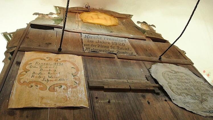 Historische Spuren hinter dem Altar: Erinnerungstafeln der Renovierer. Darunter ist auch die, die Mesner Albert Schmitt nach der Innenrenovierung 1996 selbst gemalt hat (links unten). Fotos: Brigitte Krause