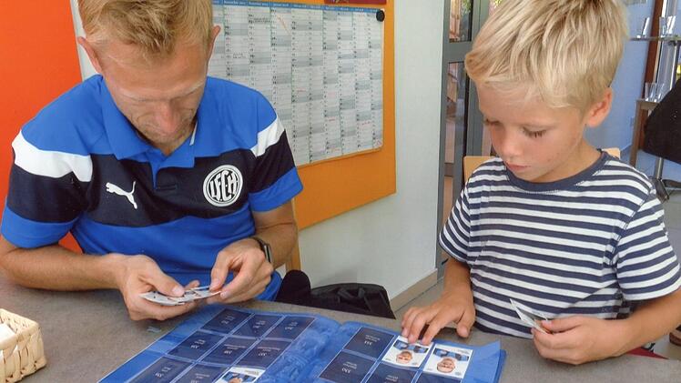 Fußballer Marco Müller und ein junger Sammler sichten die Bilder, die sie noch gut gebrauchen können.
