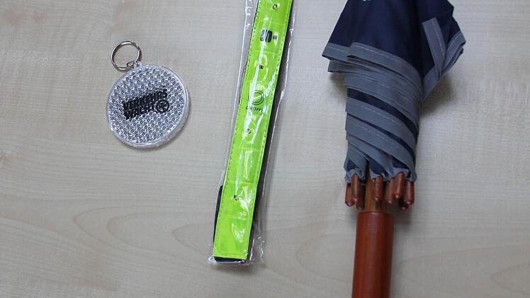 Günstige Sachen, mit denen man nachts besser gesehen wird: Der "Blinki" der Verkehrswacht, das neongelbe Klettarmband mit roten Leuchtdioden und der Verkehrswacht-Regenschirm, bei dem der graue Rand das Licht reflektiert.  Foto: Friedwald Schedel