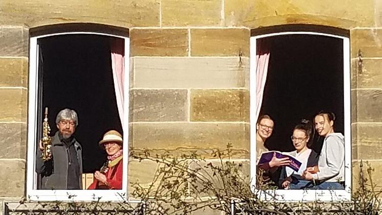 Thomas und Marion Reich musizieren im linken Fenster, die Töchter Rahel, Rut und Sara singen und musizieren im rechten Fenster des Pfarrhauses in Trieb. Foto: pr