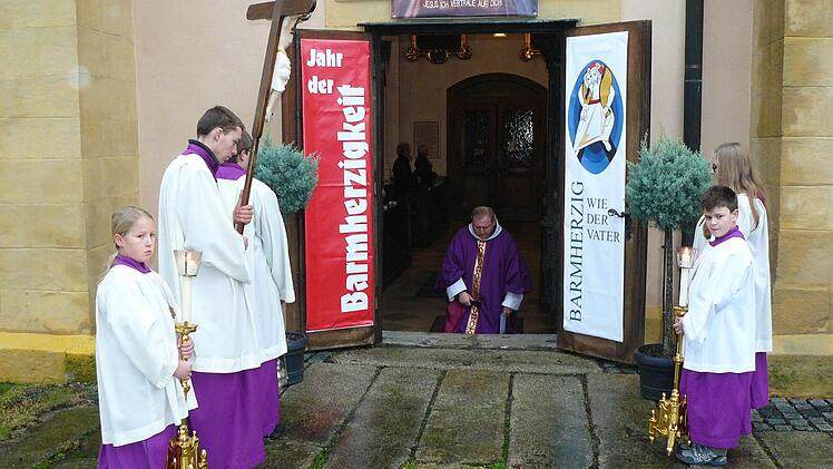 Pater Adrian hat die "Pforte der Barmherzigkeit" am Südportal der Wallfahrtsbasilika Marienweiher geöffnet und spricht kniend ein Gebet. Fotos: kpw