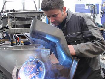 Oldtimer-Restaurationen sind eine Spezialität von Christopher Schorsch. Hier schweißt er am Kotflügel eines Opel Rekord Olympia, Baujahr 1957. Im Hintergrund ist die Karosserie eines Mercedes 280 SL aus dem Jahr 1968 zu sehen. Foto: Jürgen Gärtner