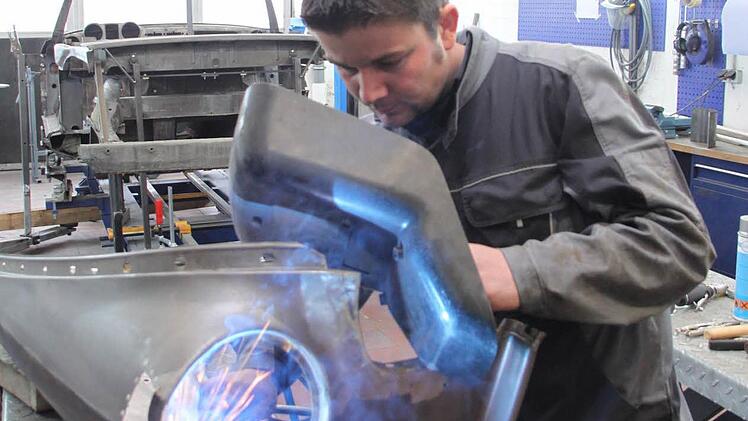 Oldtimer-Restaurationen sind eine Spezialität von Christopher Schorsch. Hier schweißt er am Kotflügel eines Opel Rekord Olympia, Baujahr 1957. Im Hintergrund ist die Karosserie eines Mercedes 280 SL aus dem Jahr 1968 zu sehen. Foto: Jürgen Gärtner