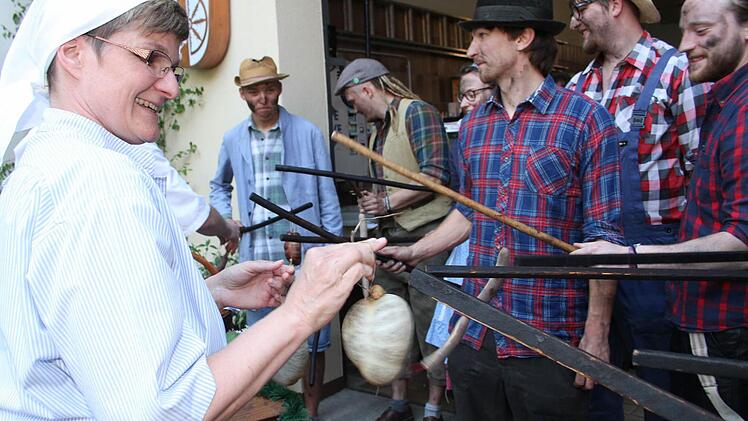 Tanja Sagner hängt einen dicken Presssack an die Stecken der Willmersreuther "Woschdfohrer". Auf die Trage wurde bereits ein großer Topf mit Wurstbrühe gestellt. So ist es Brauch bei der "Krumba". Fotos: Sonny Adam