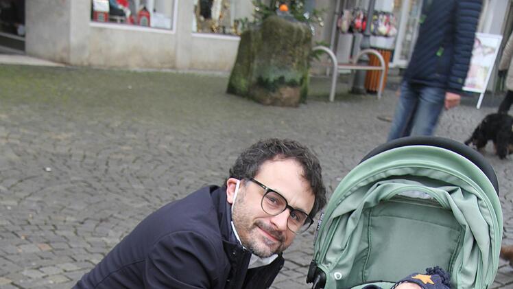 Florian Weid (40) hat seinem Sohn Theo (1) eine Weihnachtsbratwurst gekauft. Florian Weid ist Kulmbacher, wohnt aber in Bad Kreuznach. "Ich w&auml;re jetzt durch die Obere Stadt, um alte Bekannte zu treffen. Das vermisse ich schon", sagt er. Foto: Sonny Adam