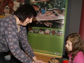 Uschi Prawitz, Leiterin der Mupäz-Juniorakademie, zeigt Maya Hermann, wie man Kakaosplitter richtig zerkleinert. Das Pulver schmeckt allerdings noch nicht süß. Fotos: Sonja Adam