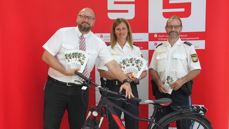 Bei der Verkehrsaktion verlost die Stadt- und Kreissparkasse Erlangen H&ouml;chstadt Herzogenaurach mit Filialleiter Axel Geier (links) in Kooperation mit der Polizei, vertreten durch Michaela Rosenthal und Thomas Gamm, am kommenden Mittwoch  ein Fahrrad. Foto: Mirjam Stumpf