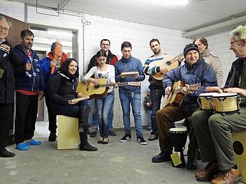 Musik verbindet: Einige Asylbewerber aus Ebern probieren ihre neuen Instrumente aus. Zusammen mit Franz-Josef Zeher vom Asylhelferkreis (links), Peter "Fuffy" Schmitt (dritter von links), Robert Stoppa (Mitte hinten), Katrin Lurz (Dritte von rechts) und Christina Kohmaier-Widhalm (sitzend) sowie Alfred Neugebauer (rechts) vom Caritas-Kindergarten "Arche Noah" Ebern.  Foto: Johanna Eckert