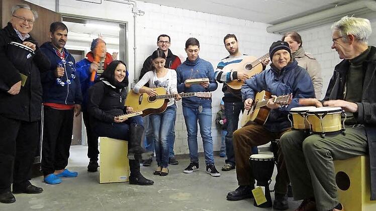 Musik verbindet: Einige Asylbewerber aus Ebern probieren ihre neuen Instrumente aus. Zusammen mit Franz-Josef Zeher vom Asylhelferkreis (links), Peter "Fuffy" Schmitt (dritter von links), Robert Stoppa (Mitte hinten), Katrin Lurz (Dritte von rechts) und Christina Kohmaier-Widhalm (sitzend) sowie Alfred Neugebauer (rechts) vom Caritas-Kindergarten "Arche Noah" Ebern.  Foto: Johanna Eckert