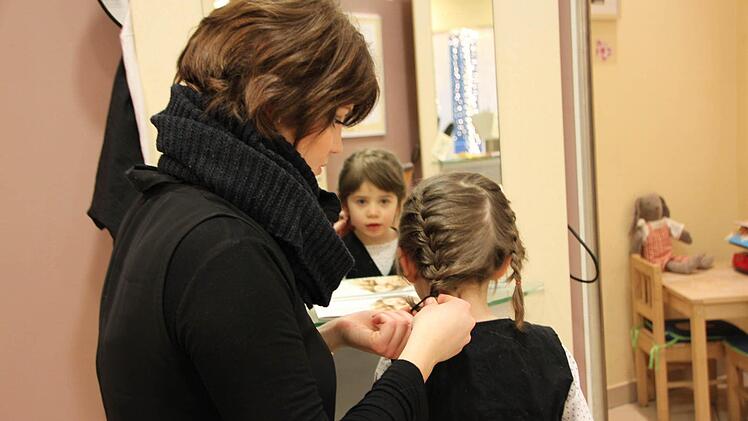 Frisiert werden wie die Großen: Die vierjährige Cara Sophia Kehm darf ausnahmsweise auf Muttis Arbeit in Bad Brückenau vorbeischauen. Viktoria Liebhardt, Auszubildende im dritten Lehrjahr, flicht ihr die Haare. Foto: Ulrike Müller