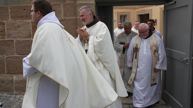 Die drei Franziskaner Patres Bonifaz Suhak (links) und Rufus Witt (rechts neben ihm) sowie Kosma Rejmer (hinten links) ziehen mit anderen Geistlichen vom Innenhof des Klosters in die Pfarrkirche.