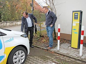 Edgar Müller (links) von Bayernwerk und Steinbachs Bürgermeister Thomas Löffler stöpseln ein E-Auto an die Ladesäule an. Foto: pr