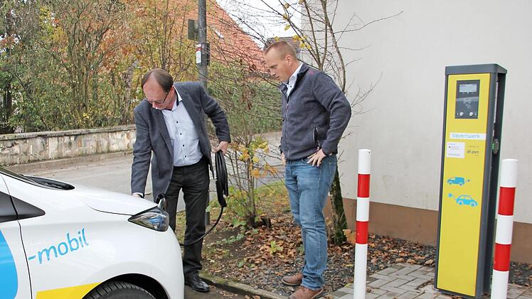 Edgar Müller (links) von Bayernwerk und Steinbachs Bürgermeister Thomas Löffler stöpseln ein E-Auto an die Ladesäule an. Foto: pr