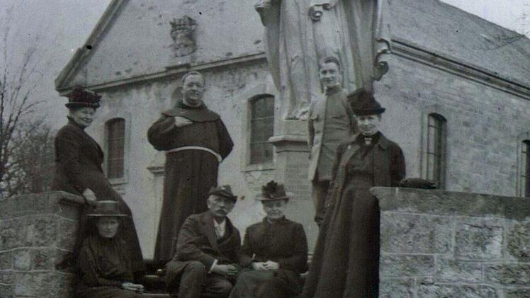 Eine kleine Reisegesellschaft in den 1920er Jahren, begleitet von einem Franziskaner-Pater vor der Wallfahrtskirche auf dem Maria Ehrenberg