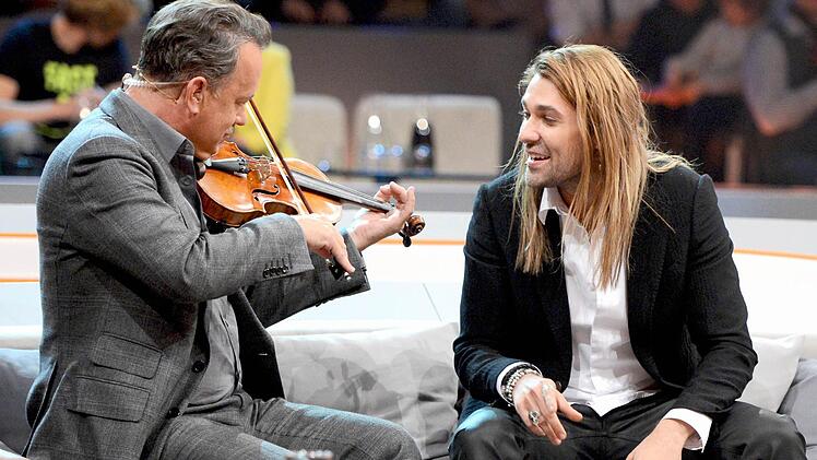 US-Schauspieler Tom Hanks (l) spielt am 03.11.2012 in der ZDF-Show &laquo;Wetten, dass..?&raquo; in der &Ouml;VB-Arena in Bremen auf der Geige von Violinist David Garret. Foto: Sascha Baumann/ZDF/dpa