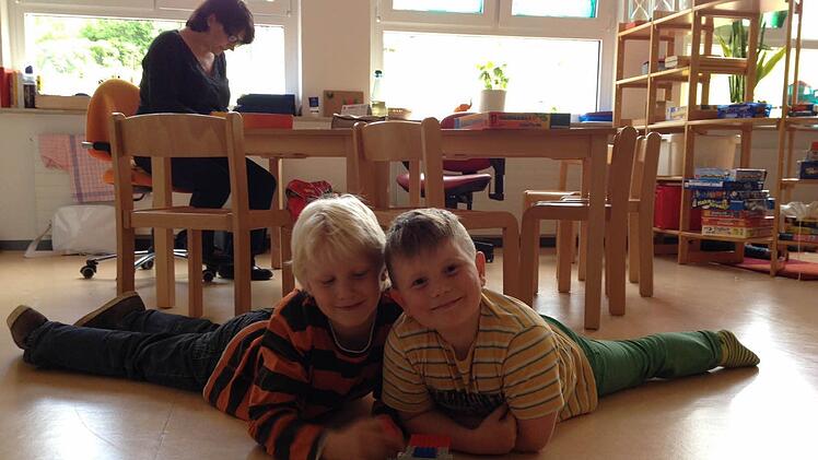 Robin (links) und Ciaron haben Freizeit und spielen mit Lego-Bausteinen auf dem Fußboden. Sie werden von Silke Helget beaufsichtigt. Foto: Alexandra Wirth
