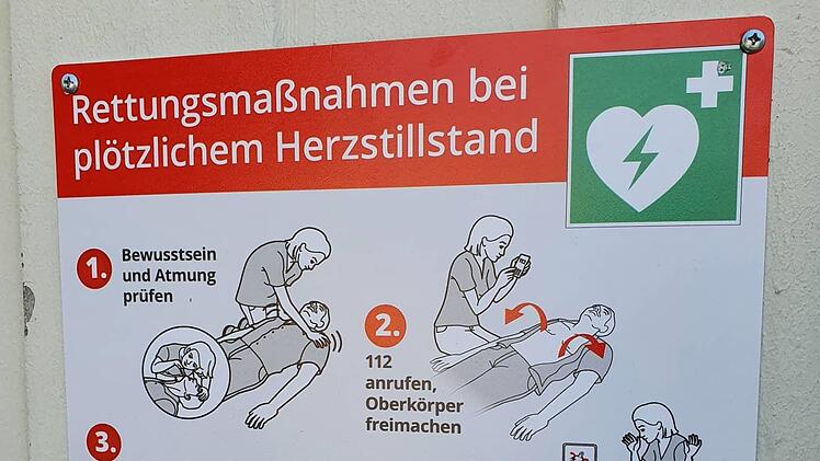 Auf einem Schild wird kurz erkl&auml;rt, wie der Defibrillator anzuwenden ist.