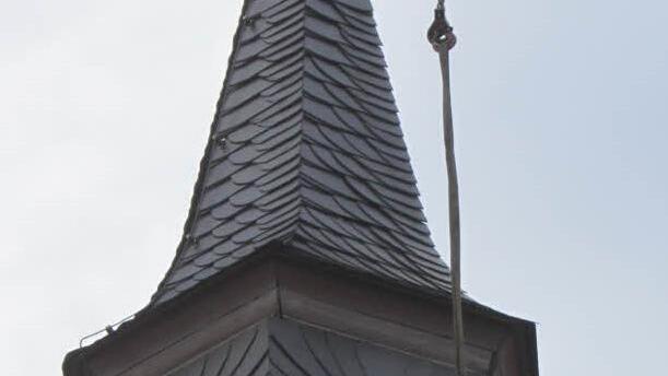 Ein Arbeiter nimmt die erste Glocke im Dachreiter der Kapelle in Empfang. Foto: Matthias Einwag