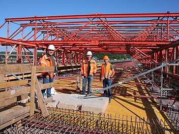 Mario Urschlechter (von links), Markus Mayer und Hartmut Metz stehen auf dem Schalwagen, der aktuell in den Stahl-Überbau der Thulbatalbrücke eingepasst wird. Foto: Ralf Ruppert