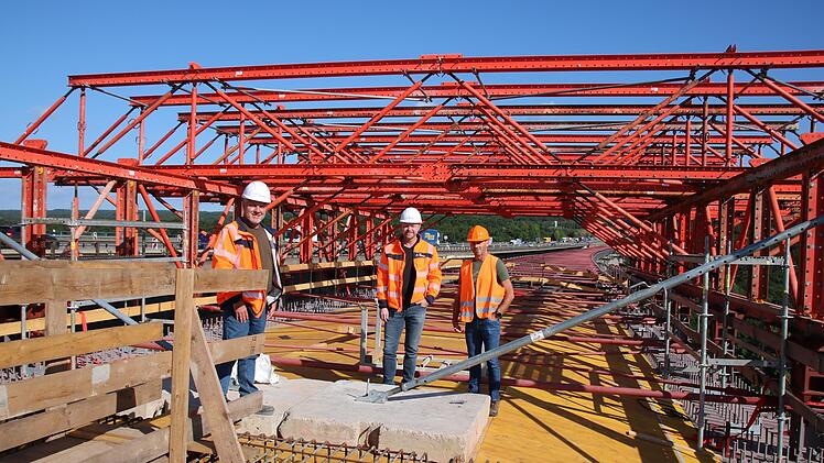 Mario Urschlechter (von links), Markus Mayer und Hartmut Metz stehen auf dem Schalwagen, der aktuell in den Stahl-Überbau der Thulbatalbrücke eingepasst wird. Foto: Ralf Ruppert