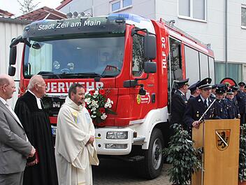 Die Zeiler Feuerwehr mit Kommandant Tobias Hetterich (am Rednerpult) war vor dem neuen Auto angetreten, als es übergeben wurde. Mit im Bild, von links: der Zeiler Bürgermeister Thomas Stadelmann, der frühere Gemeindereferent Helmut Leykauf und Pfarrer Michael Erhart.  Foto: Klaus Schmitt