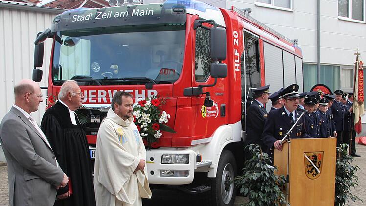 Die Zeiler Feuerwehr mit Kommandant Tobias Hetterich (am Rednerpult) war vor dem neuen Auto angetreten, als es übergeben wurde. Mit im Bild, von links: der Zeiler Bürgermeister Thomas Stadelmann, der frühere Gemeindereferent Helmut Leykauf und Pfarrer Michael Erhart.  Foto: Klaus Schmitt