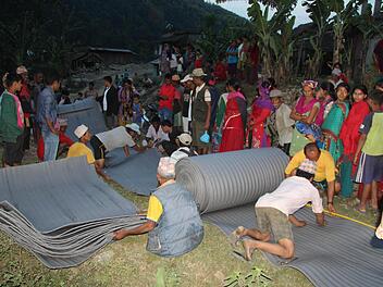 Aus nahe gelegenen Bergdörfern kamen die Menschen zur Verteilungsstelle. Hier schneiden Helfer gerade Isomatten zu, damit die Notleidenden nicht länger in Zelten auf dem blanken Boden schlafen müssen. Foto: FriendCircle WorldHelp