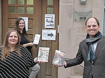 Michael Hofmann überreicht die beiden Bücher an Büchereileiterin Beate Knörlein und Sandra Adelhardt (hinten) von der Gemeindebücherei St. Bartholomäus in Kirchehrenbach.