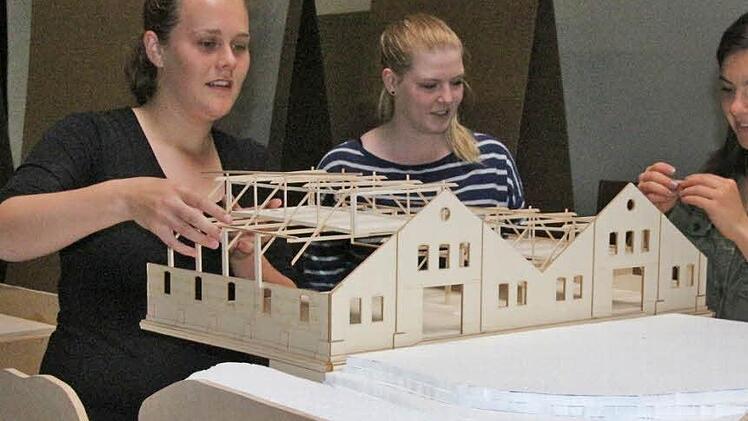 Anna-Maria Braun, Sarah Miller und Elisabeth Stölzl, Architekturstudentinnen im vierten Semester, setzen ihr Berghallen-Modell auf eine Landschaft aus Styropor. In ihrem Studienprojekt ging es um die mögliche Umnutzung der Berghallen auf dem Hofbräugelände. Foto: Simone Bastian
