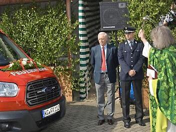 Pater Helmut Haagen (in Grün) nahm die Segnung des neuen Mannschaftstransportwagens vor - rechts Bürgermeister Hans Pietz. Foto: K.-H. Hofmann