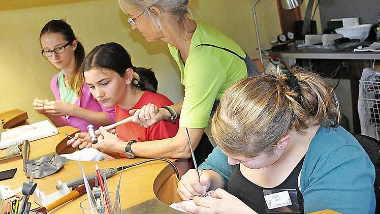 Conny Müller (stehend) erklärt Marie, Anna und Amelie (von links), wie Silber mit einem Hammer strukturiert wird.  Foto: Simon Albrecht