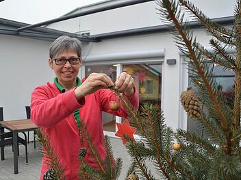 Petra Popp ist seit September als gerontopsychiatrische Fachkraft im Pflegeheim "Rhönblick" tätig. In den vergangenen Wochen hat sie viel mit den Bewohnern gebastelt, so auch den Christbaumschmuck. Hier hängt sie einen Apfel daran. Foto: Kathrin Kupka-Hahn