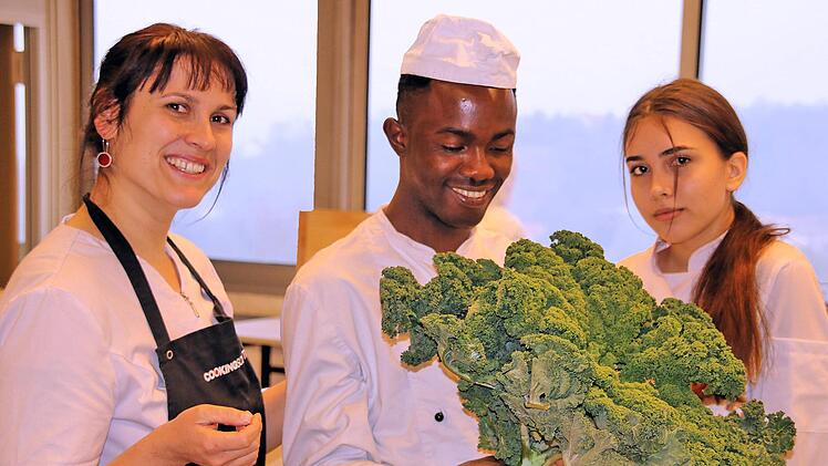 Ein Prachtexemplar von Grünkohl präsentiert hier Hadi aus Gambia, der an  der Berufsfachschule für Ernährung und Versorgung eine Ausbildung macht.  Links seine Lehrerin Katharina Zeller, rechts seine Kollegin Jule.Dieter Britz