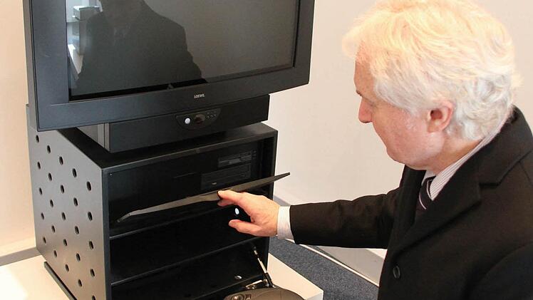 Loewe-Pressesprecher Roland Raithel zeigt den Xelos. Dabei handelt es sich 1995 um den ersten Fernseher, mit dem man im Internet surfen konnte. Im Rack war ein  Computer eingebaut, der über eine Infrarot-Tastatur bedient werden konnte.