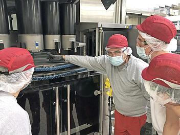 Ausbilder Norbert R&ouml;der und seine Auszubildenden in der Produktion bei Coca-Cola in Knetzgau: Der Ausbilder erkl&auml;rt den Inspektor an der Abf&uuml;llanlage, der die Mehrweg-Glasflaschen auf Verschmutzung und Besch&auml;digung pr&uuml;ft. Von links: Jasmin Wilhelmy (Auszubildende), Norbert R&ouml;der (Ausbilder), Levin Prediger (Auszubildender) und Dominik Metzner (Auszubildender).  Foto: Coca-Cola/Manuel Schlapka