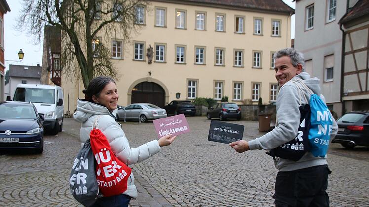 Christine Schikora und Arno Reuscher präsentieren die Rucksäcke und Frühstücksbrettchen des Gewerbevereins.