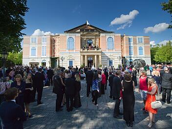 Besucher warten am 25.07.2014 bei der Eröffnung der Bayreuther Festspiele auf dem Grünen Hügel in Bayreuth bei einer unplanmäßigen Unterbrechung wegen eines technischen Defekts vor dem Festspielhaus. Die Richard-Wagner-Festspiele sind eines der wichtigsten kulturellen und gesellschaftlichen Ereignisse Deutschlands. Foto: Tobias Hase/dpa
