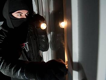 Auf diesem gestelllten Bild versucht ein Einbrecher, durch ein Fenster in eine Wohnung einzudringen. Foto: Andreas Gebert, dpa