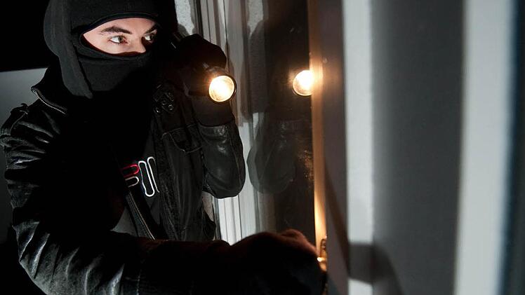 Auf diesem gestelllten Bild versucht ein Einbrecher, durch ein Fenster in eine Wohnung einzudringen. Foto: Andreas Gebert, dpa