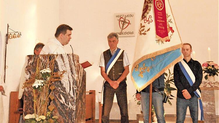 Die Fahnenabordnung des 1. FC Pressig hat sich im Altarbereich aufgestellt, Pfarrer Detlef Pötzl leitet die Weihehandlung für die Traditionsfahne ein.