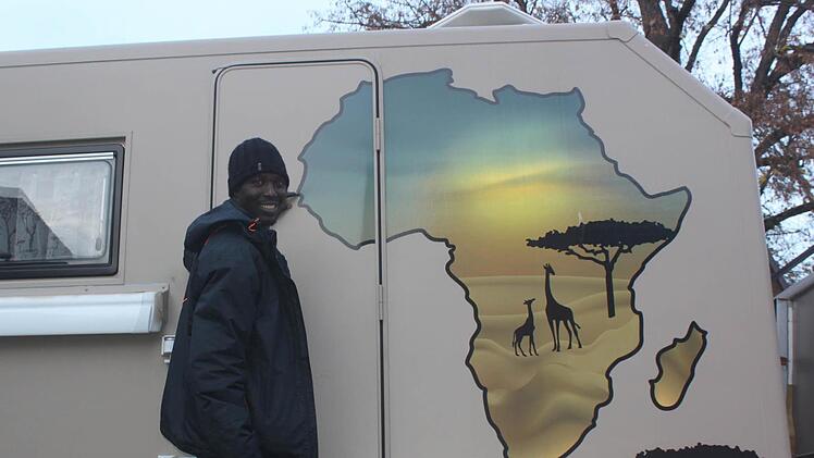 Bruno Diouf vor dem Afrika-Logo, das auf dem Lkw angebracht ist. Foto: Matthias Einwag