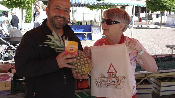 Eine der Ersten, die mit der neuen Einkaufstasche zum "Shoppen" ging, war Eva Albert (rechts). Der Händler Michele Gentile packte ihr eine Ananas auf dem "Grünen Markt" ein.  Foto: Winfried Ehling