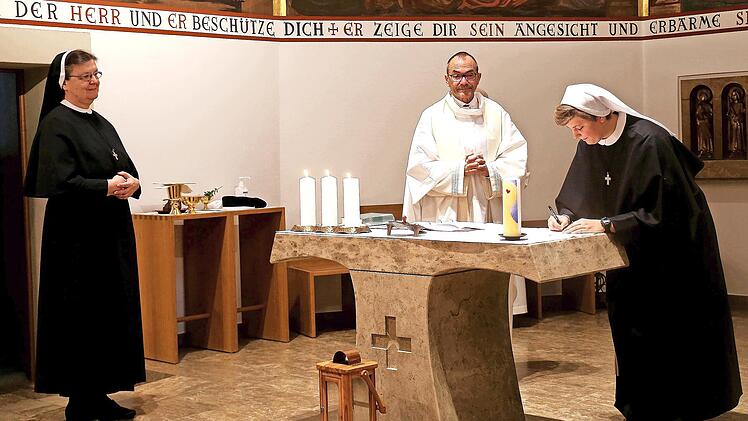 Schwester Magdalena unterschreibt im Beisein von Kongregationsleiterin Schwester Regina und Pfarrer Roland Huth die Professformel am Altar.