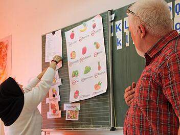 Bernhard Schmitt (rechts) übt mit den Asylbewerbern aus Riedenberg Vokabeln rund um einen Obstsalat. Foto: Ulrike Müller